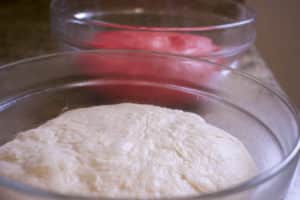 white and red colored bagel dough in bowls after rising