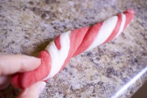 long strip of red and white bagel dough being twisted