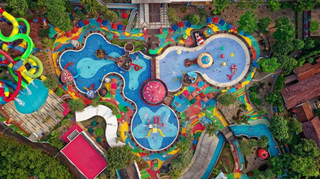 top down view of a colorful water park with umbrellas, pools, and rides