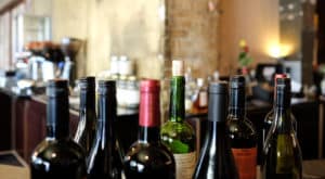 Various sizes and colors of wine bottles set out on an indoor counter top.