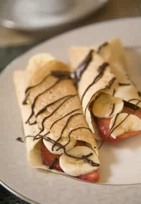 two crepes with chocolate drizzle on plate